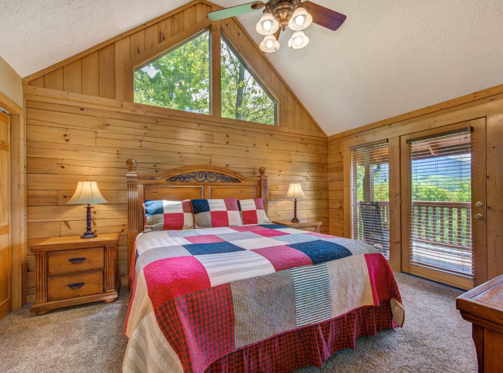 Drift off in your cozy cabin bedroom, where rustic charm meets comfort beneath soaring ceilings and natural light.