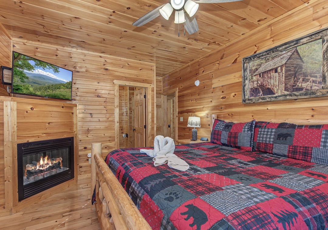 Cozy up in your rustic bedroom featuring warm wood walls, fireplace, and comfortable bed with mountain-themed bedding for perfect cabin vibes.
