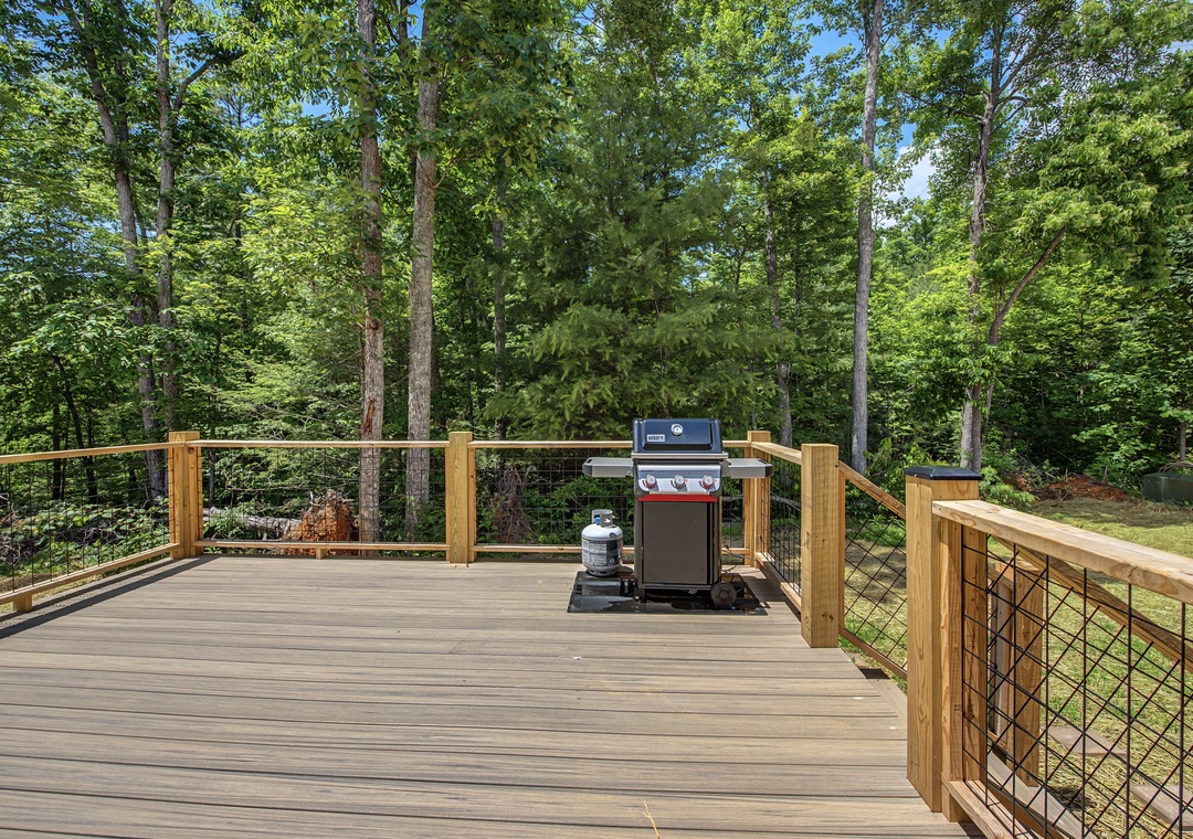 A spacious deck surrounded by lush forest offers the perfect setting for grilling meals and enjoying peaceful outdoor moments amid nature's beauty.