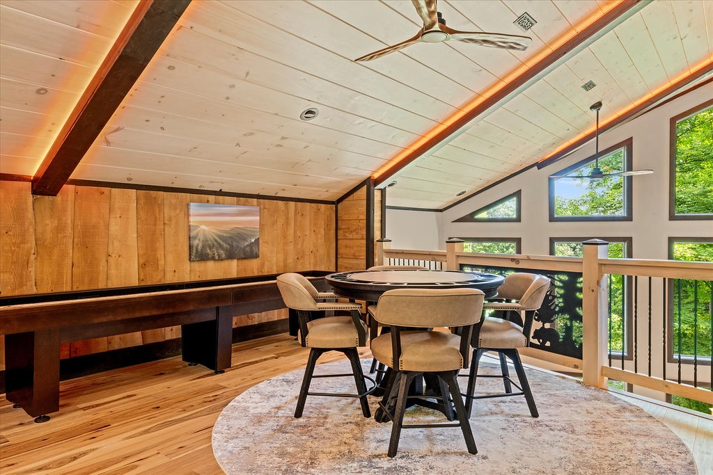 Unwind in your loft game room with friends around the card table, enjoying soaring ceilings, warm wood accents, and stunning treetop views through expansive windows.