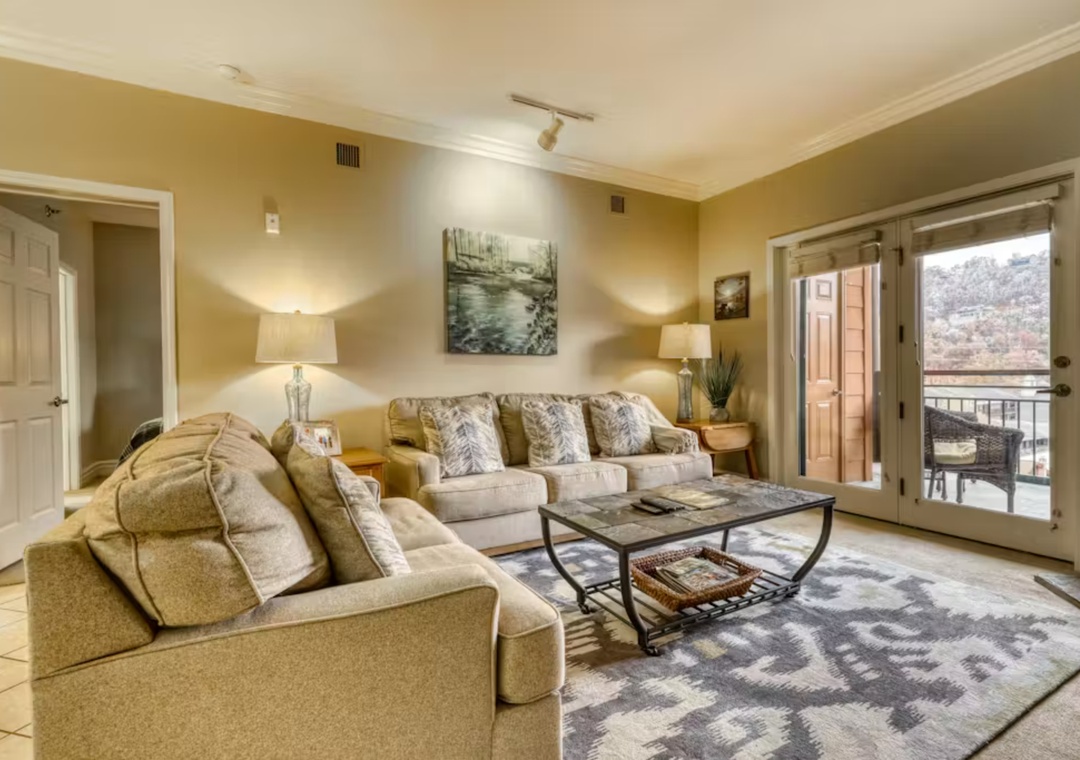 Sink into plush sofas in your spacious living room, where natural light streams through balcony doors and thoughtful decor creates the perfect retreat.