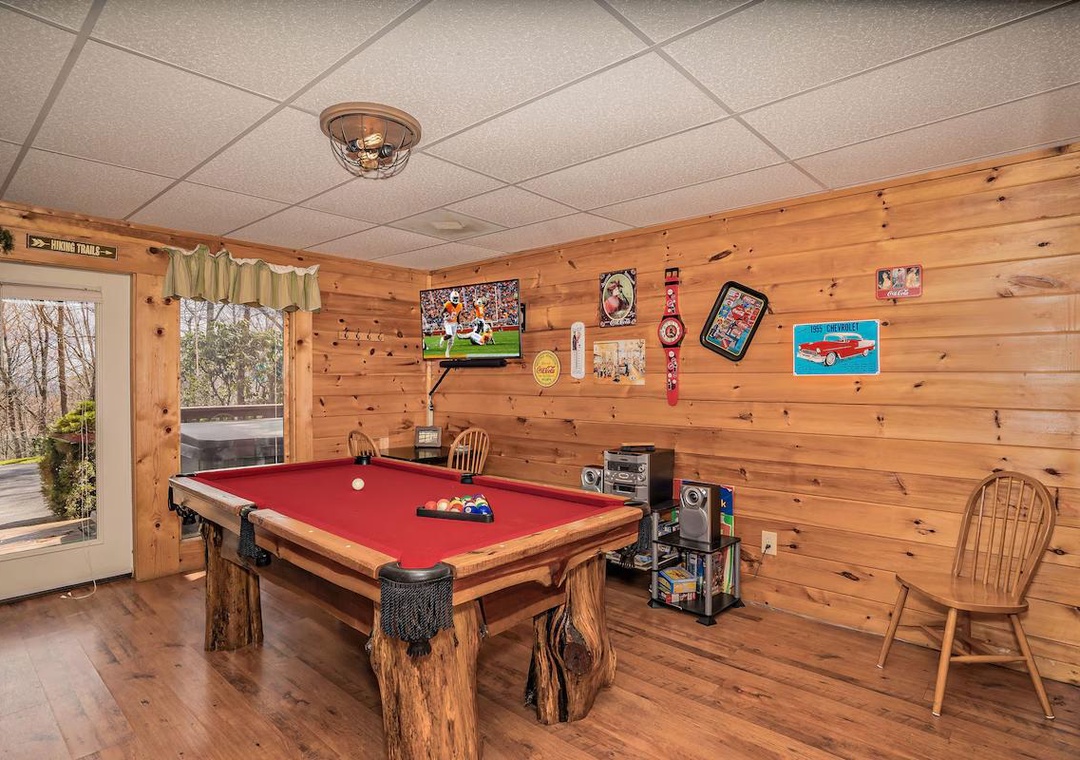 Challenge friends to a game of pool in your cozy game room, complete with rustic wood walls and entertainment center.