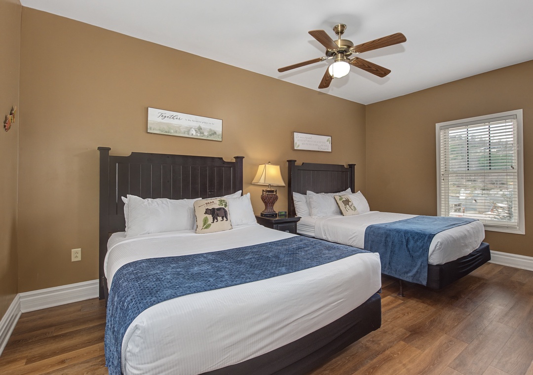 Relax in your spacious bedroom with two plush beds, warm earth tones, and a ceiling fan to keep you cool.