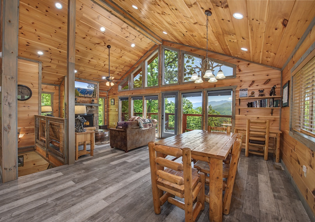 Step into your open-concept retreat, where vaulted wood ceilings soar above and floor-to-ceiling windows frame breathtaking mountain views. Gather around the rustic dining table or relax by the fireplace, then step out to your private deck surrounded by n