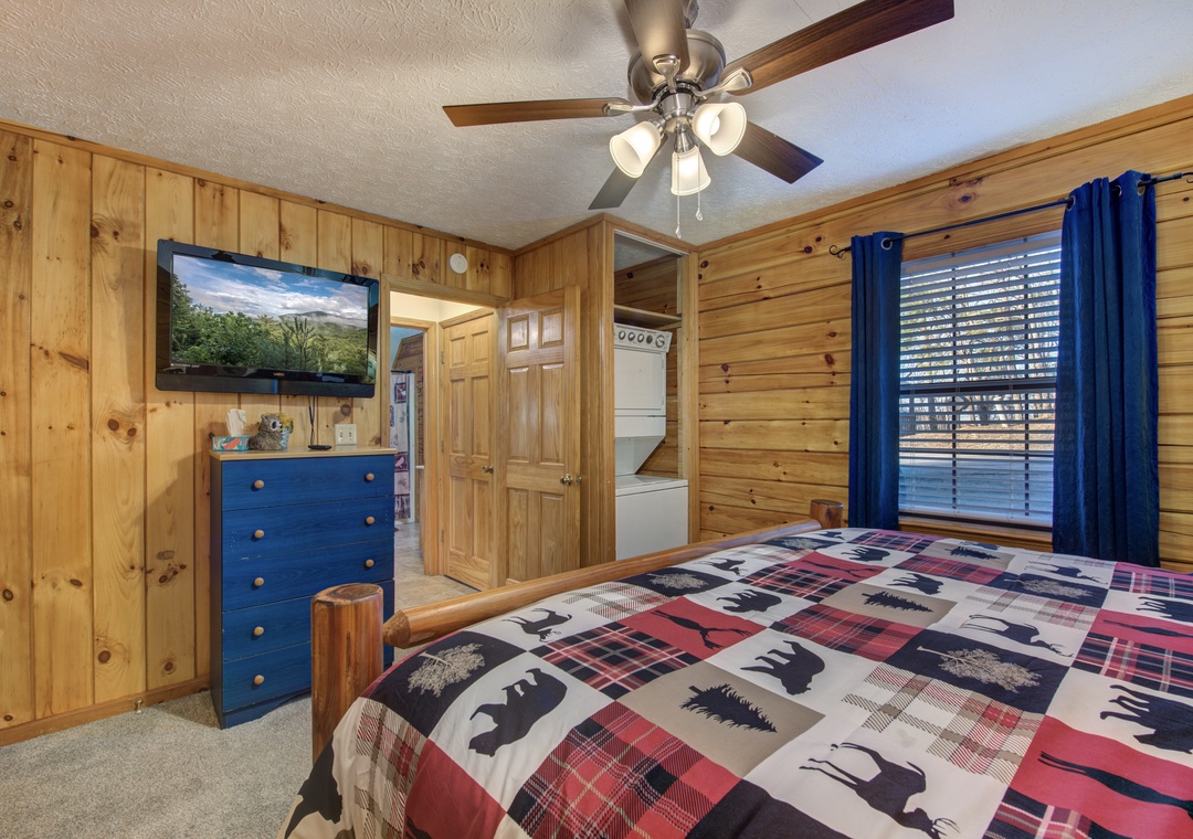 Cozy rustic bedroom with warm wood paneling, wildlife-themed bedding, and convenient in-room laundry access for your mountain getaway.