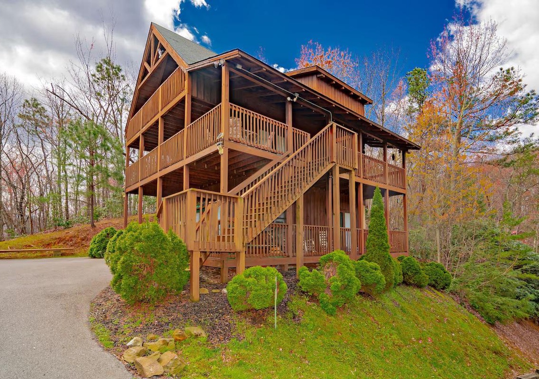 Beautiful mountain cabin with wraparound decks showcasing autumn colors and forest surroundings.