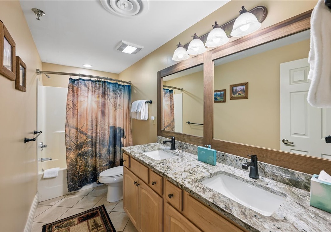 Your spacious bathroom features dual sinks with granite countertops, warm lighting, and a relaxing tub-shower combo for unwinding after your adventures.