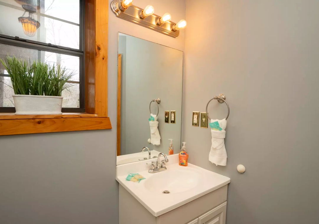 Start your day in this bright, well-appointed bathroom featuring warm wood accents and thoughtful amenities for your comfort.