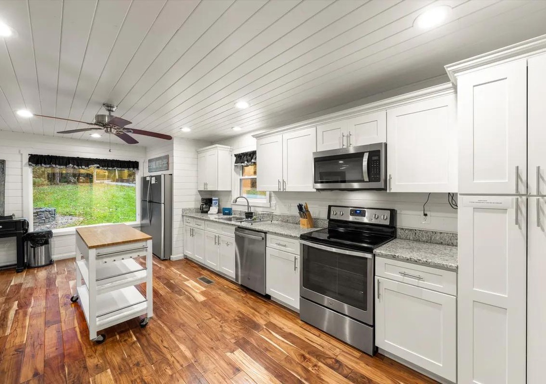 Step into your bright, fully-equipped kitchen with warm wood floors, crisp white cabinetry, and stainless steel appliances ready for your culinary adventures.