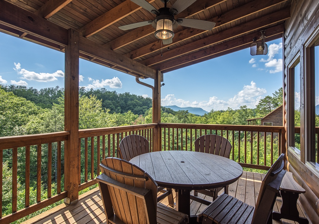 Enjoy your morning coffee on this covered deck, surrounded by lush forest and distant mountain views. The outdoor dining table invites you to savor meals in fresh air.