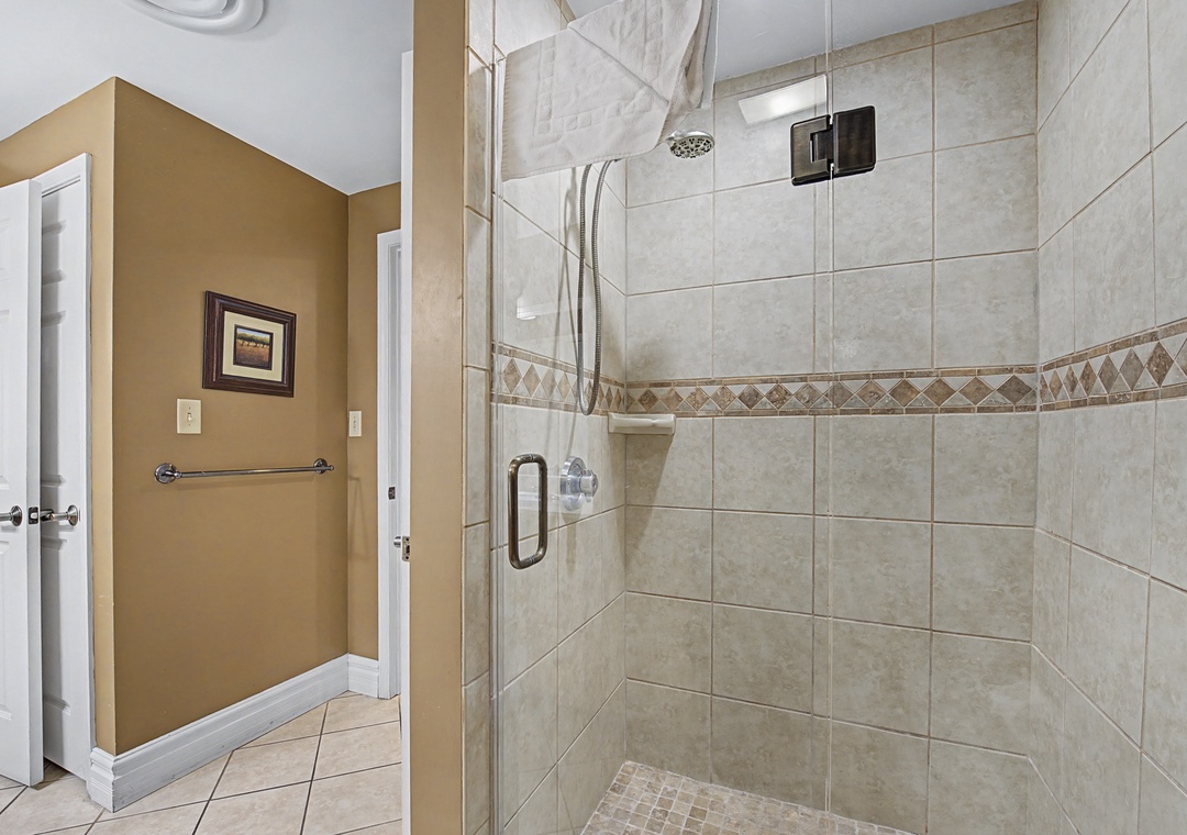 Step into your private spa retreat with a spacious tiled shower featuring elegant stone accents and modern glass doors.