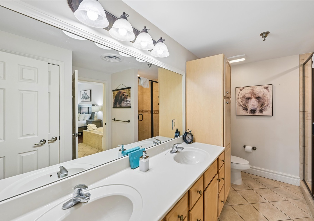 Freshen up in your spacious dual-sink bathroom with warm wood vanity, bright lighting, and modern fixtures.
