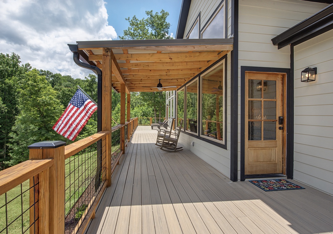 A welcoming deck with covered pergola, rocking chairs, and hot tub overlooking peaceful wooded surroundings. The perfect spot to unwind after exploring the area.