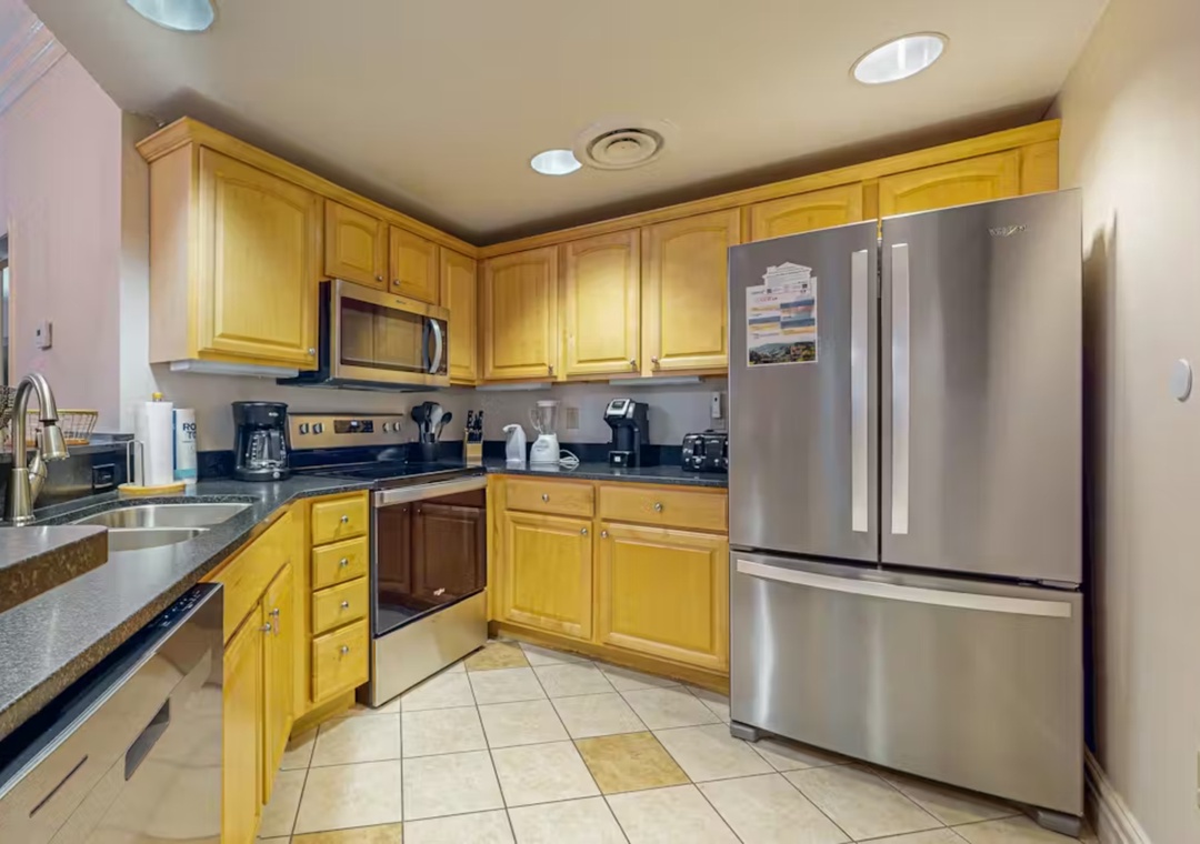 Your fully equipped kitchen awaits with granite counters, stainless steel appliances, and warm wood cabinets—perfect for preparing meals.