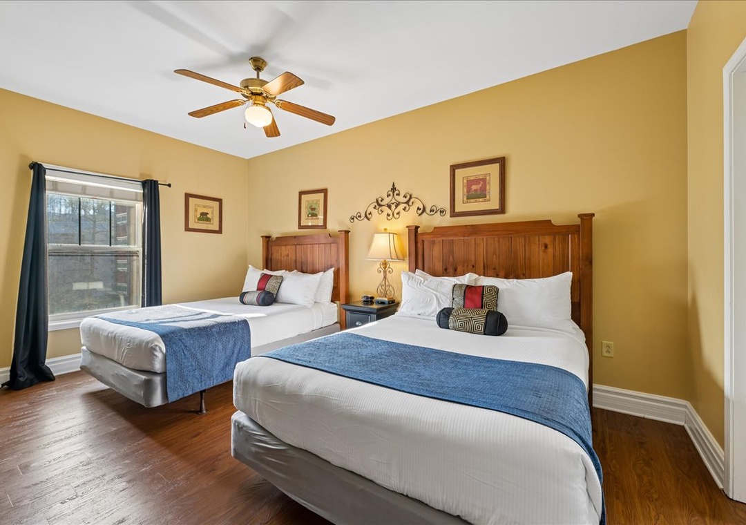 Unwind in your comfortable twin bedroom with warm wood accents, crisp linens, and a gentle ceiling fan for perfect relaxation.