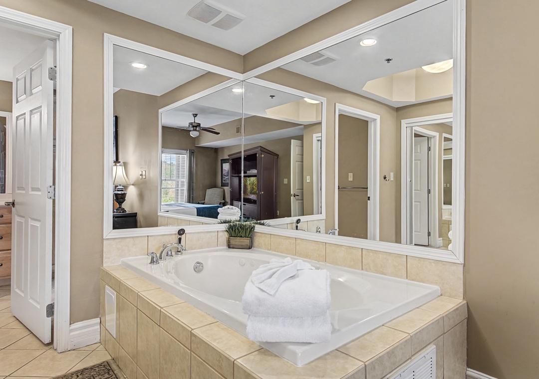 Unwind in your private spa-like bathroom with a luxurious soaking tub surrounded by elegant mirrors and soft lighting.