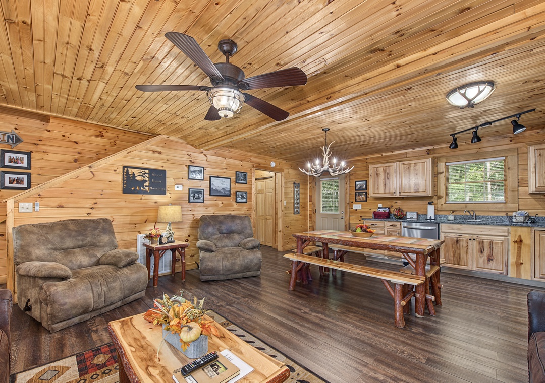 Relax in your cozy cabin retreat with rustic wood ceilings, plush seating, and a fully equipped kitchen perfect for family meals. Natural light pours through the windows, creating a warm and welcoming space.