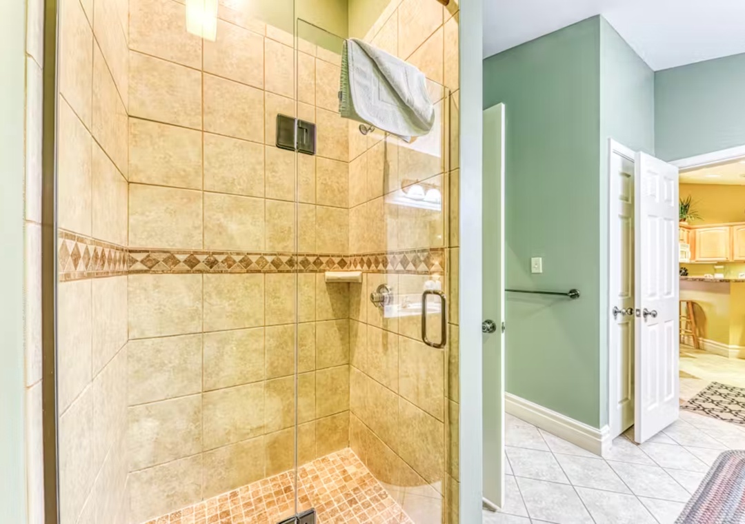 Step into your elegant tiled shower with glass doors, where fluffy towels await your refreshing morning routine.