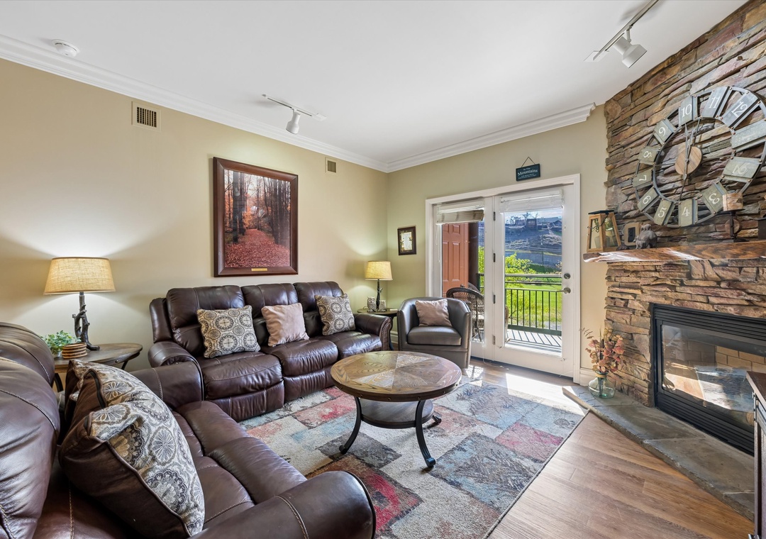 Sink into plush leather seating beside your stone fireplace, where natural light streams through patio doors revealing mountain views.