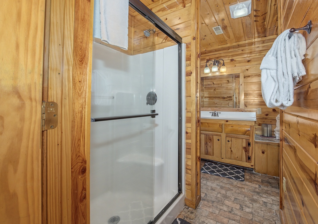 Step into your private retreat—warm wood surrounds you, soft robes await, and a spacious shower invites you to wash away the day in rustic comfort.
