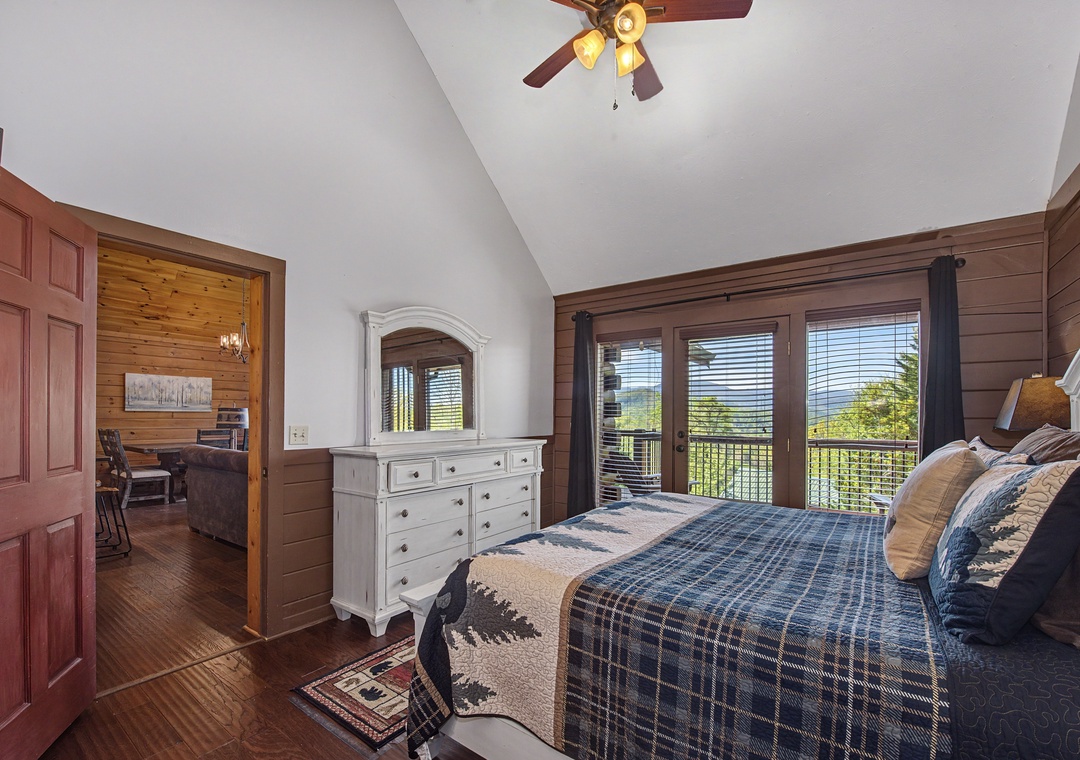 Drift off in your cozy bedroom with rustic charm, featuring plaid bedding and stunning mountain views through your private balcony doors.