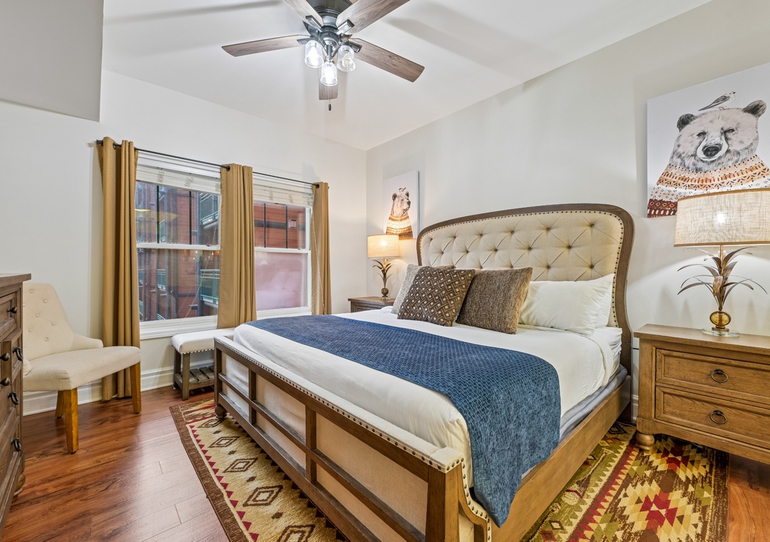 Sink into your luxurious king bed with plush linens and whimsical bear artwork creating a cozy mountain cabin vibe.
