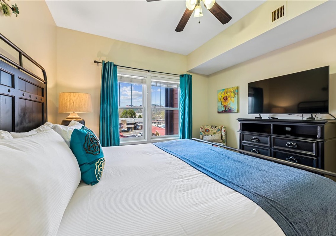 Sink into crisp white linens with turquoise accents while your ceiling fan keeps things perfectly cool. Bright windows frame peaceful views.