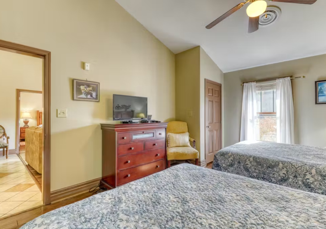 Unwind in your comfortable twin bedroom with classic furnishings, flat-screen TV, and peaceful natural light streaming through windows.