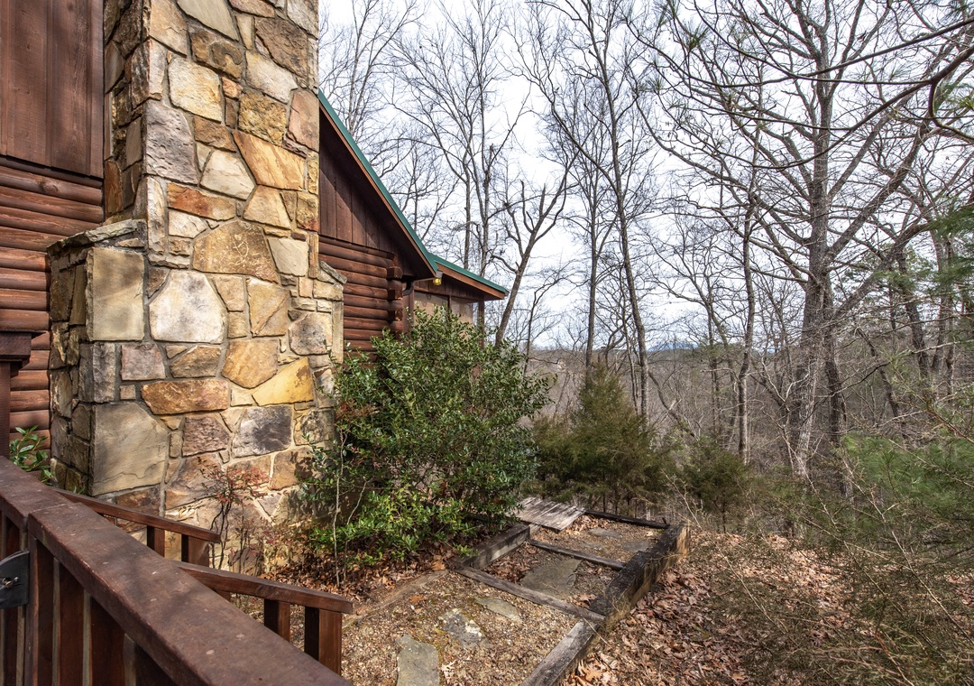 Rustic log cabin nestled in peaceful wooded surroundings with stone chimney and forest views.