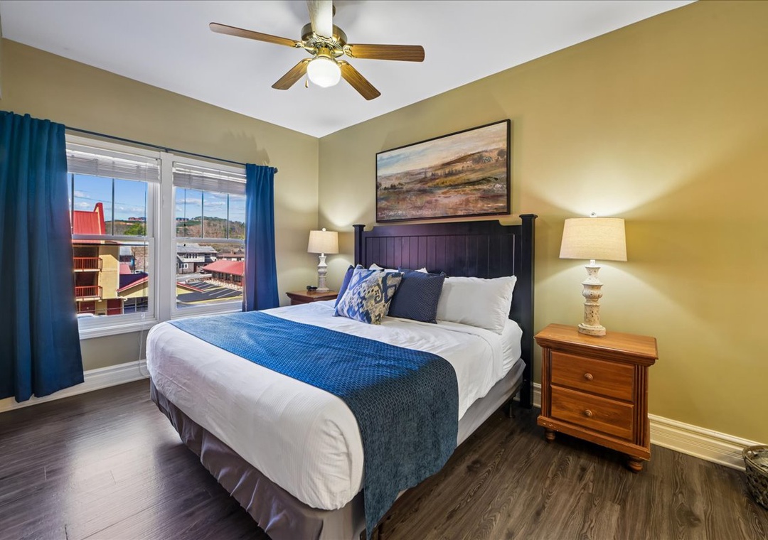 Unwind in your cozy bedroom with plush bedding, warm lighting, and peaceful city views through large windows.