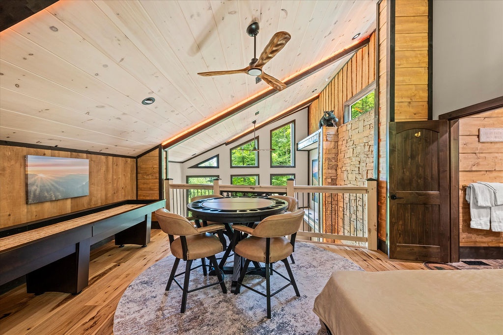 Your loft retreat features soaring ceilings, natural wood finishes, and a dedicated game table perfect for evening entertainment with mountain views through expansive windows.