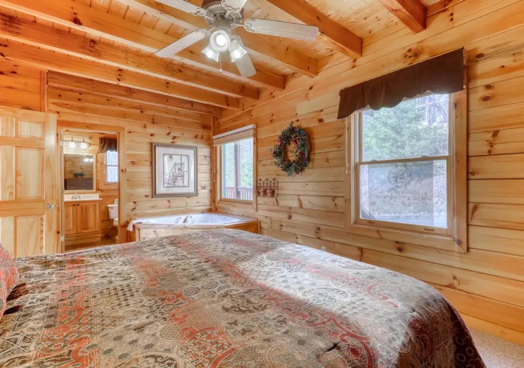 Wake up in your cozy cabin bedroom where natural wood surrounds you with warmth. A jetted tub awaits in the corner for ultimate relaxation after your adventures.
