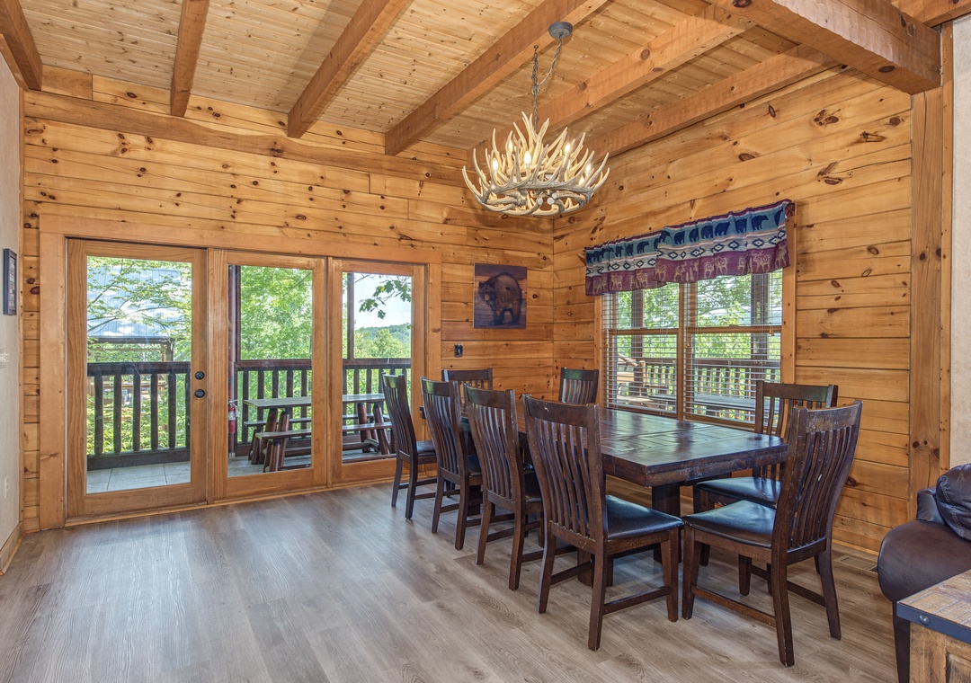 Gather around the handcrafted dining table beneath a striking antler chandelier, where warm wood walls and vaulted ceilings create an inviting mountain retreat. Step through the French doors to your private balcony and soak in peaceful wooded views.