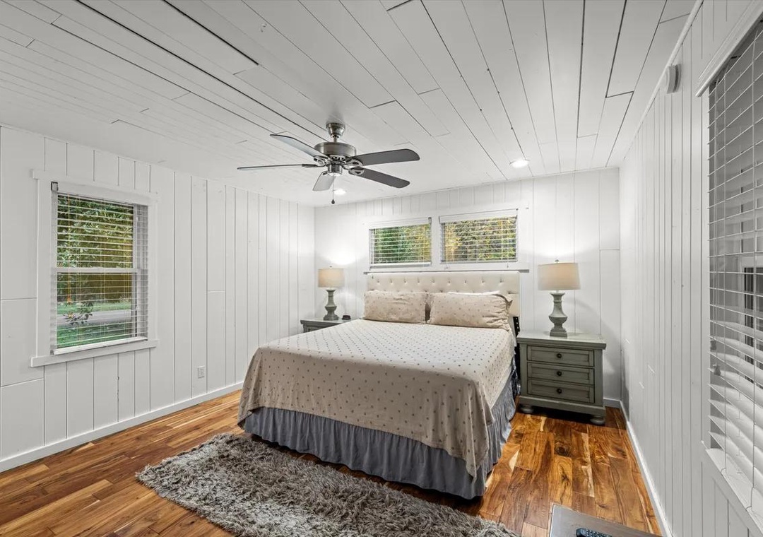 Unwind in your serene cottage-style bedroom, where warm hardwood floors and soft natural light create a peaceful haven. The ceiling fan keeps you comfortable while you relax in this cozy retreat.