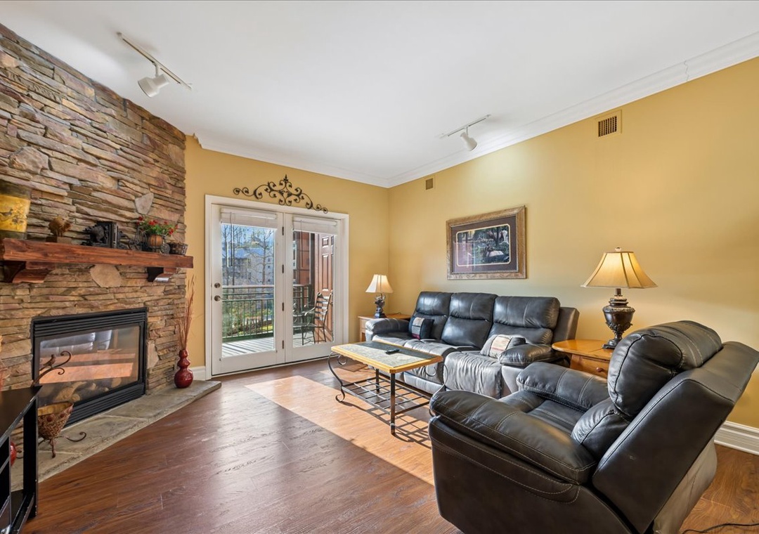 Unwind in your cozy living room with leather seating, warm fireplace, and private balcony access for peaceful moments.