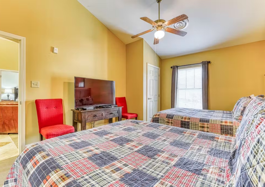 Unwind in your cheerful bedroom with twin beds, vibrant red seating, and TV entertainment after your day of adventures.