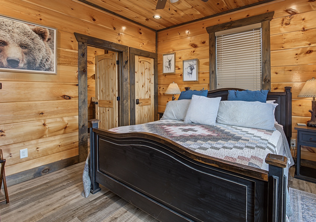 Unwind in your cozy cabin bedroom, complete with rustic wood walls, a plush bed with mountain-themed accents, and charming wildlife art that brings the wilderness inside.