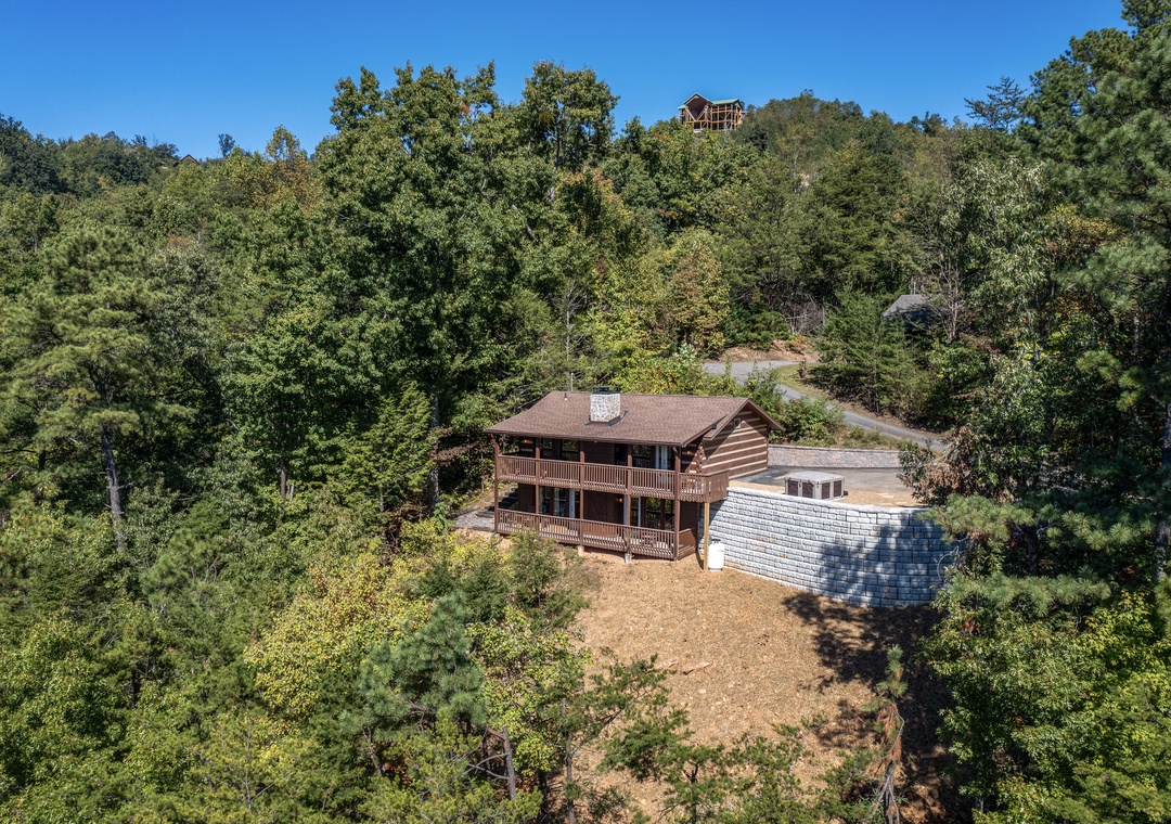 Secluded mountain retreat nestled among mature trees with expansive deck space, offering a peaceful escape surrounded by natural beauty.
