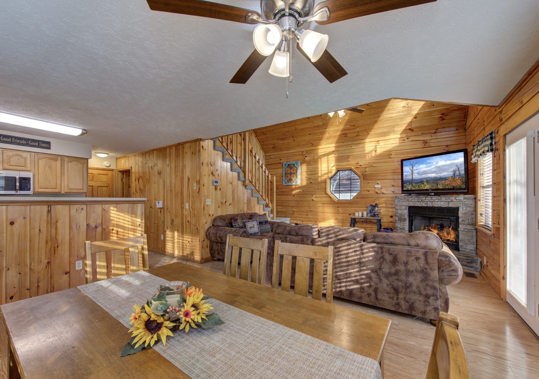 Relax in this warm, wood-paneled living space featuring comfortable seating, cozy fireplace, and open kitchen—perfect for unwinding after your adventures.