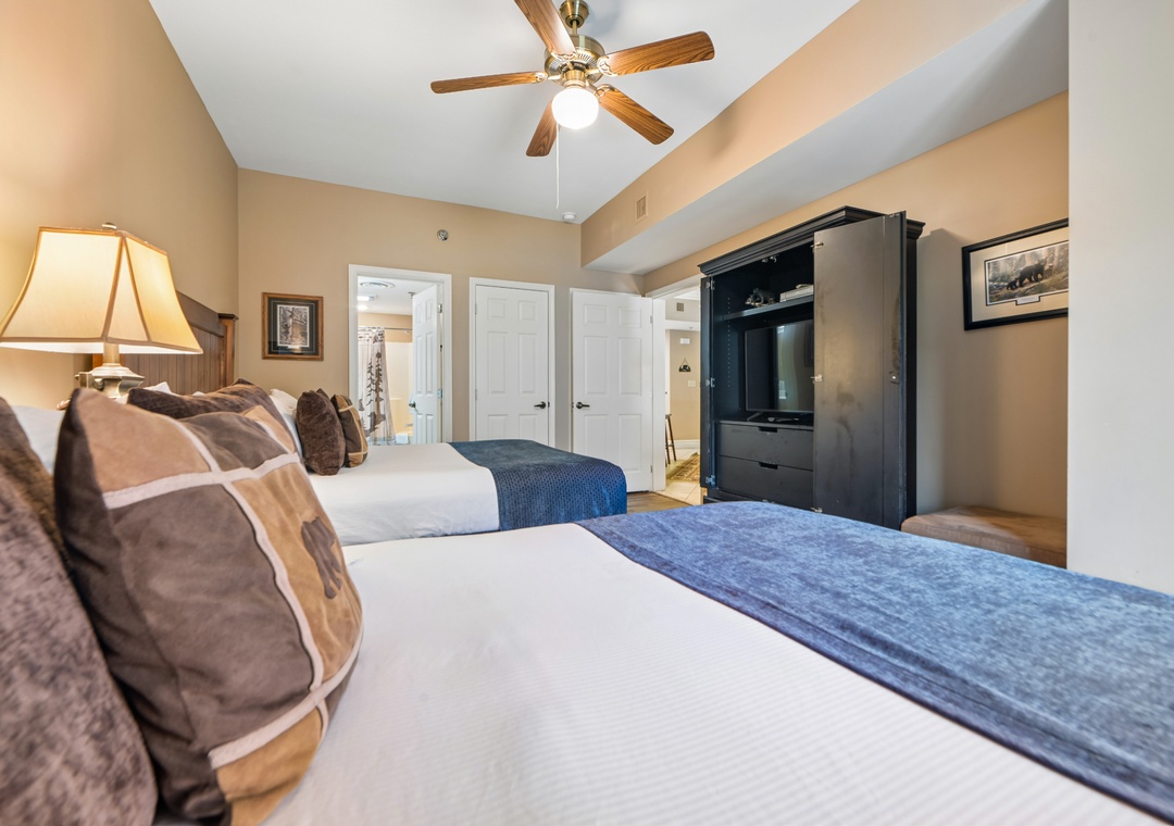 Relax in your cozy bedroom with two plush beds, warm lighting, and built-in entertainment center for ultimate comfort.