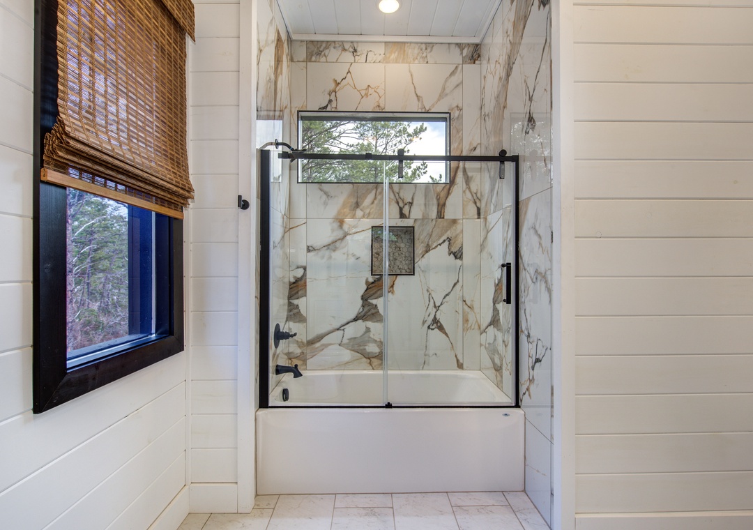Luxurious marble bathroom with elegant tub-shower combo and natural light from your window view.