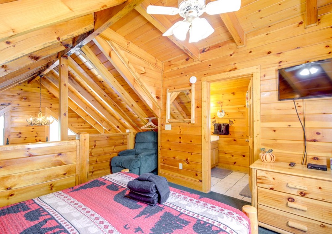 Cozy log cabin bedroom with rustic charm, soft linens, and warm wood ceiling fan to keep you comfortable.