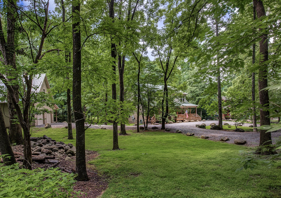 Nestled in a lush wooded setting, the property features manicured lawns, mature trees, and charming buildings offering a peaceful retreat surrounded by nature's tranquility.