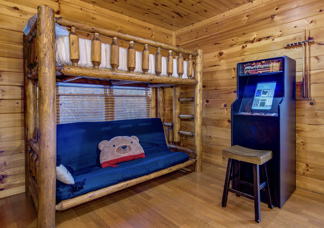 Your kids will love this cozy cabin bunk room with its handcrafted log beds and arcade-style game station, perfect for creating unforgettable family memories.