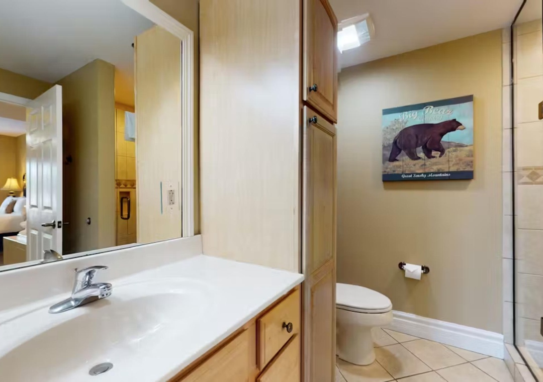 Your private bathroom features warm wood cabinetry, sleek countertops, and a refreshing shower for your comfort.