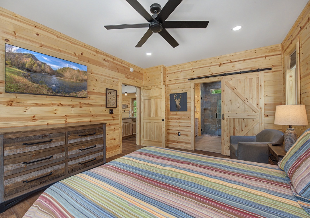 Your cozy bedroom features knotty pine walls, a plush bed with colorful linens, and your own private ensuite bathroom—perfect for unwinding after a day of adventure.