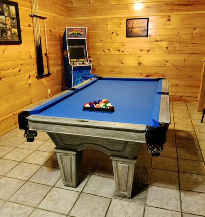 Challenge friends to pool in your cozy game room featuring rustic wood walls and arcade fun.