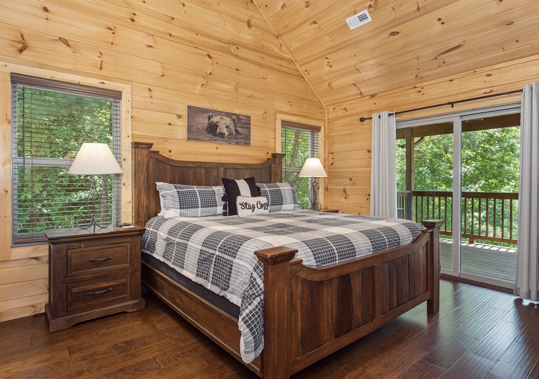 Wake up to forest views in your cozy cabin bedroom with rustic wood furnishings and a private balcony where morning coffee awaits surrounded by nature's canopy.