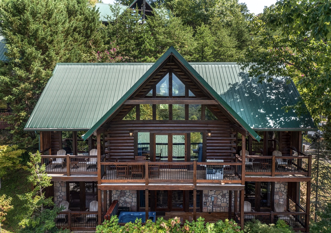 A stunning log cabin retreat featuring stone accents, spacious decks, and large windows surrounded by lush forest for the perfect mountain getaway.