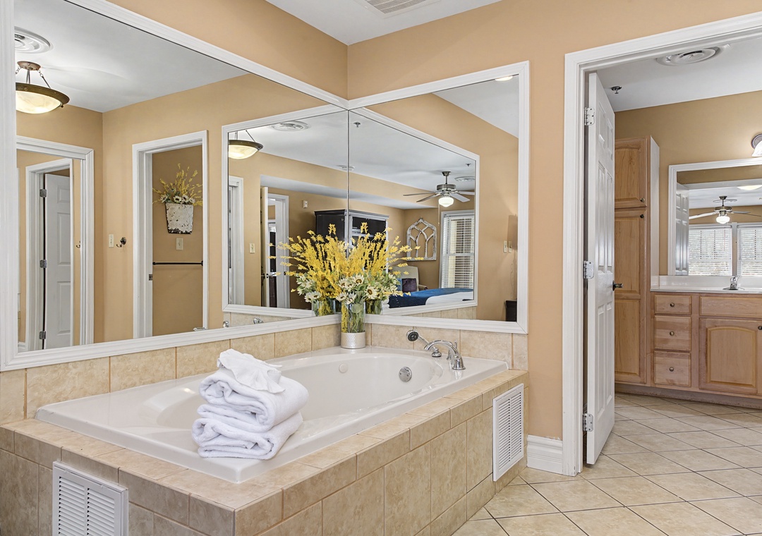 Indulge in your private spa-like bathroom featuring a luxurious soaking tub surrounded by mirrors, creating an elegant retreat for ultimate relaxation.